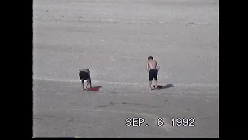 Two kids playing on a wide empty beach near the ocean