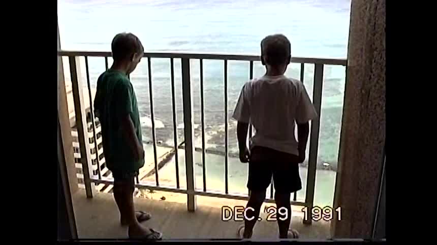 Two children look at the sea from the balcony