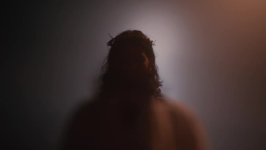 Silhouetted figure with a crown of thorns illuminated by backlight