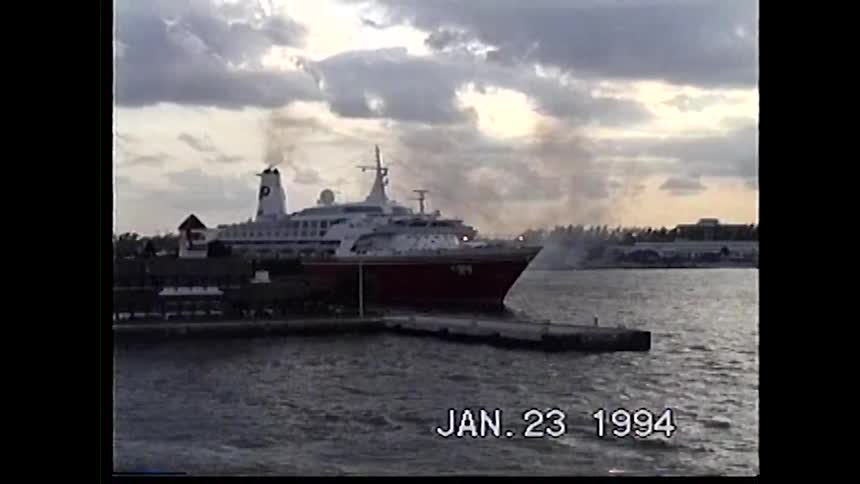 A large cruise ship is docked at a port on a cloudy day