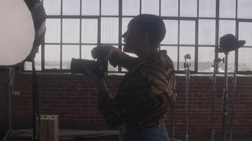 A photographer shoots inside a studio with tall industrial windows