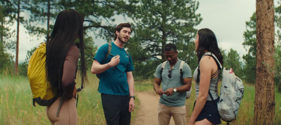 A group of friends pause and chat while hiking through a forest trail