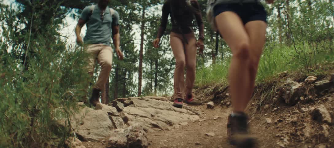 A small group of people hiking on a trail begin to run with excitement