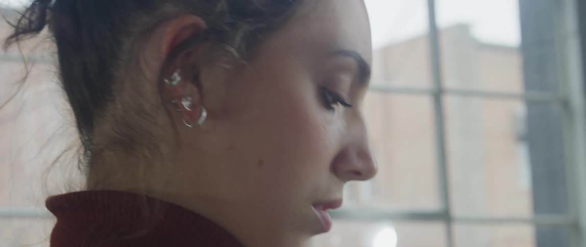 Close up of a woman in profile painting something near a window