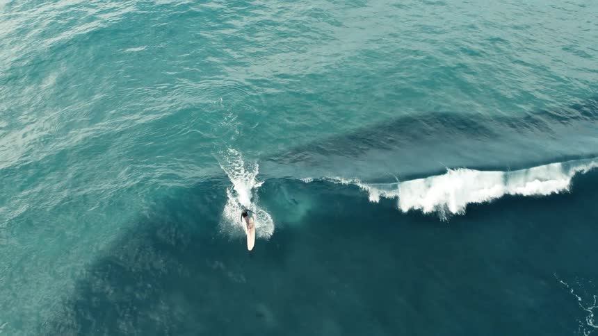 Aerial view of a surfer riding a wave as water splashes