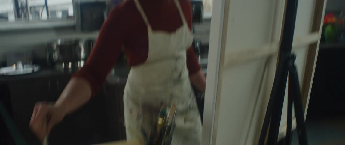 A woman painting on a large canvas in an art studio