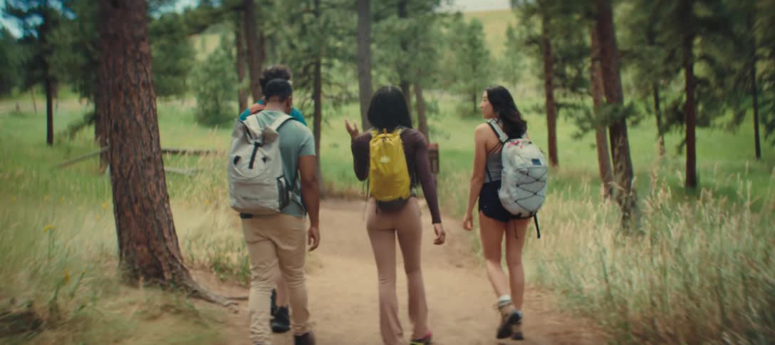 A group of four young people on a trail in a forested area