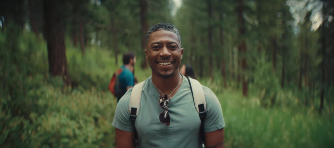 The man is smiling while hiking with friends