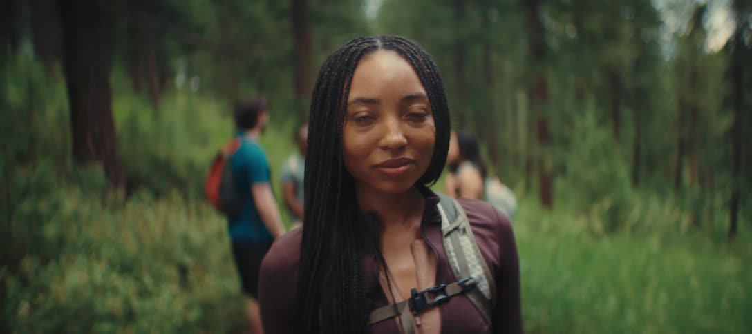 A happy woman smiling with a group of people behind her they are hiking in the middle of a forest