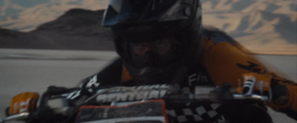 Motorcyclist wearing helmet and protective gear rides fast in a desert terrain