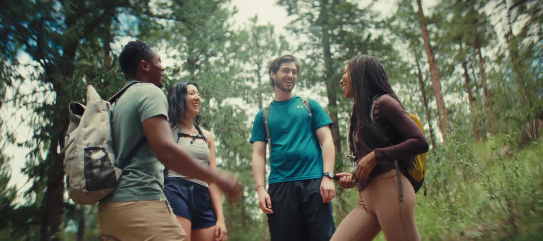 A group of friends chatting and laughing while hiking in forest
