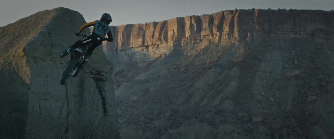 The dirt bike is jumped high in the air by the mountain