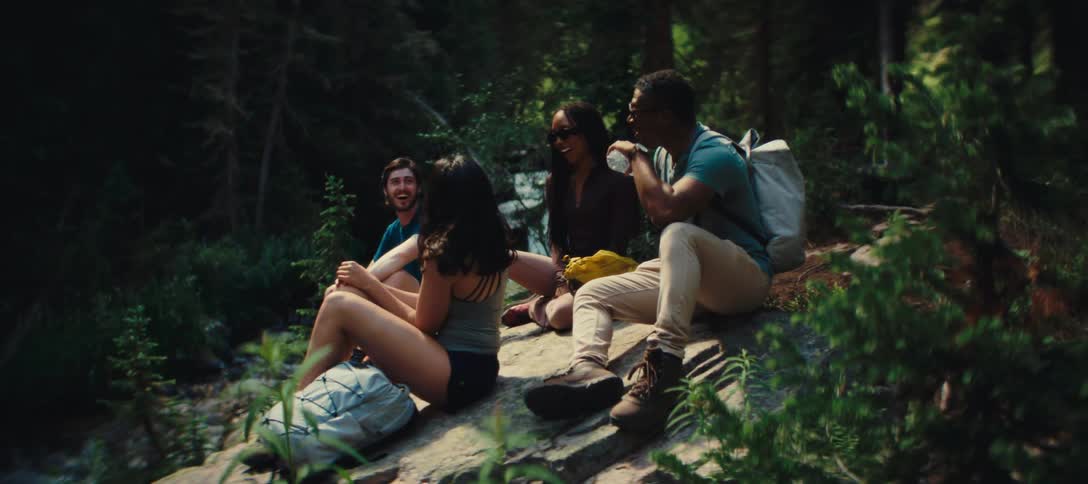 A group of friends relaxing on a rock during a forest hike