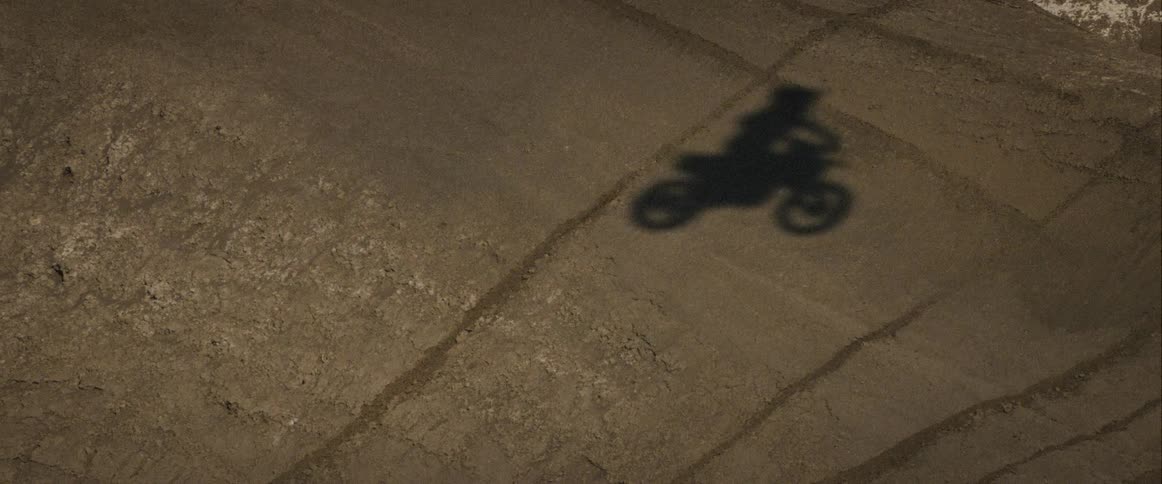 Shadow of a motorcyclist in motion cast on the dirt ground