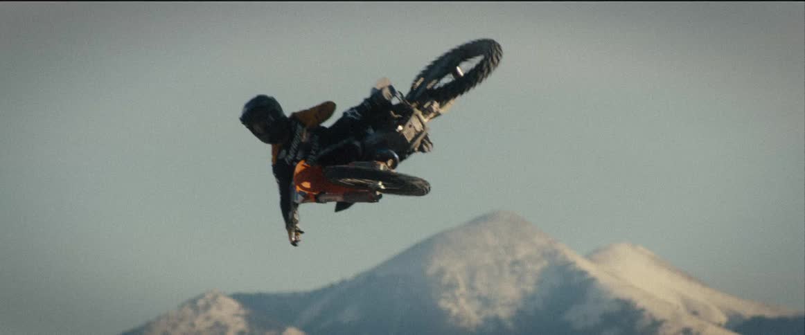Motocross rider doing a stunt over snowy mountains
