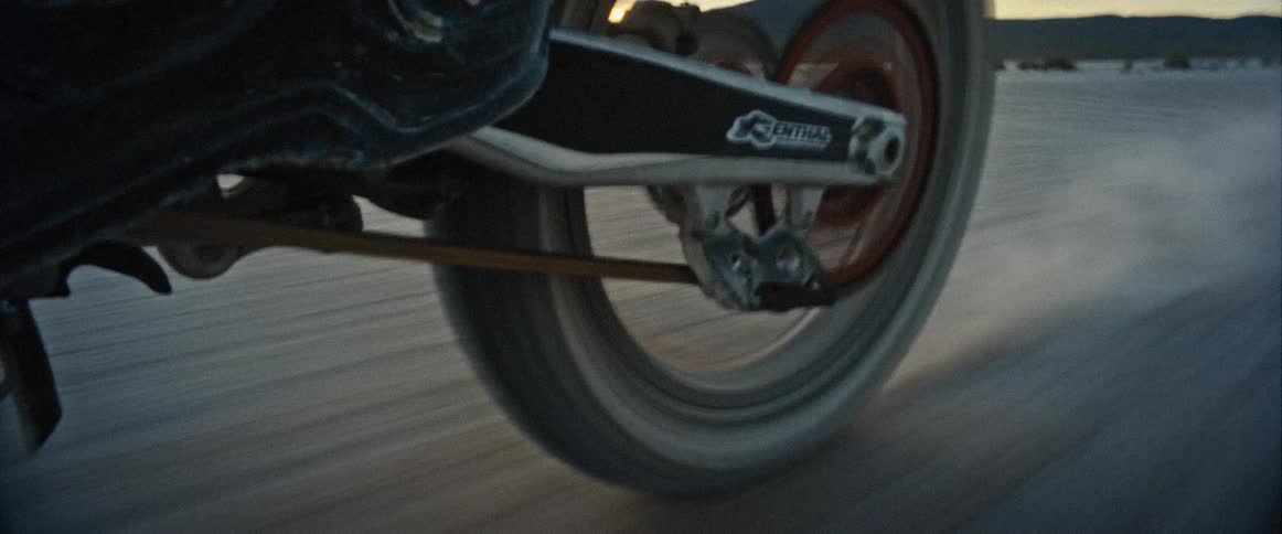 A motorcycle drives incredibly fast across a dusty landscape
