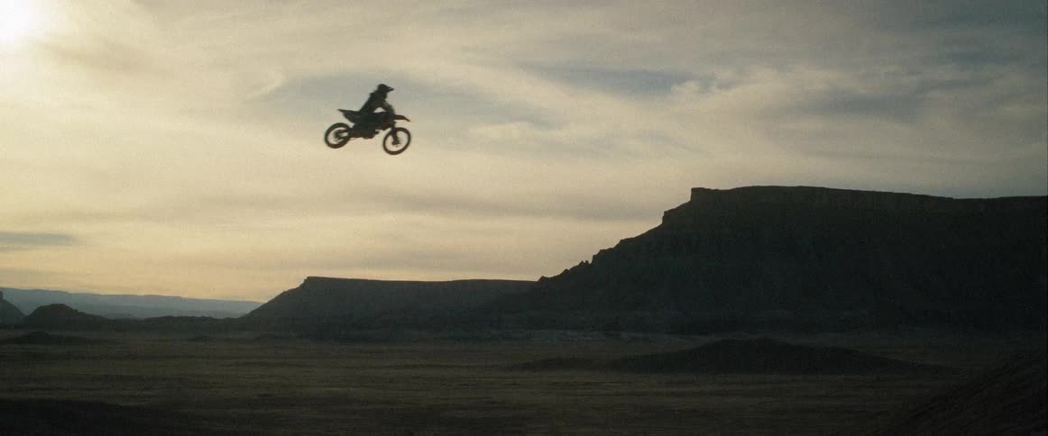 A motorbike rider jumps over a desert at sunset
