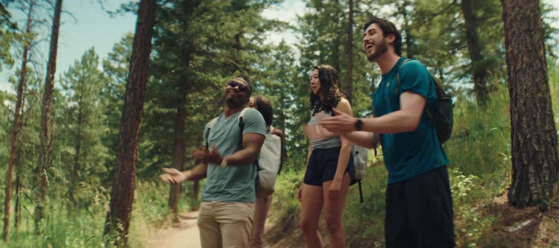A group of friends are hiking together in a forest on a sunny day