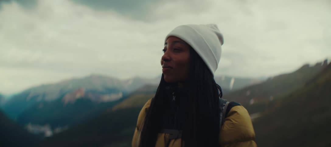Woman in a white beanie enjoys the mountain landscape in the background