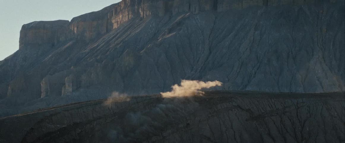 A motocross rider soars mid jump against rugged mountains