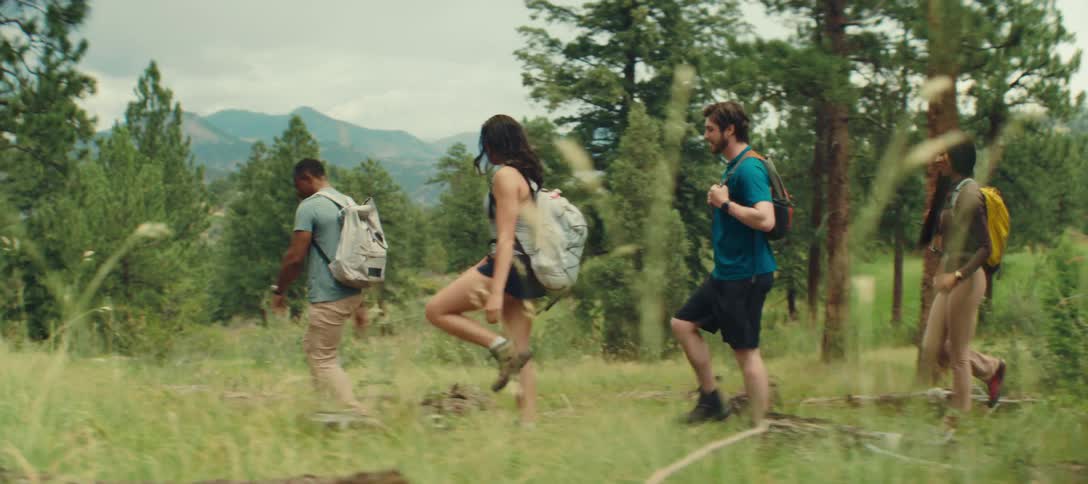 A group of friends hikes through a sunlit forest