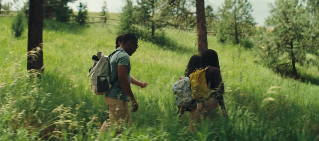 A group of four young adults are conversing while hiking outdoors