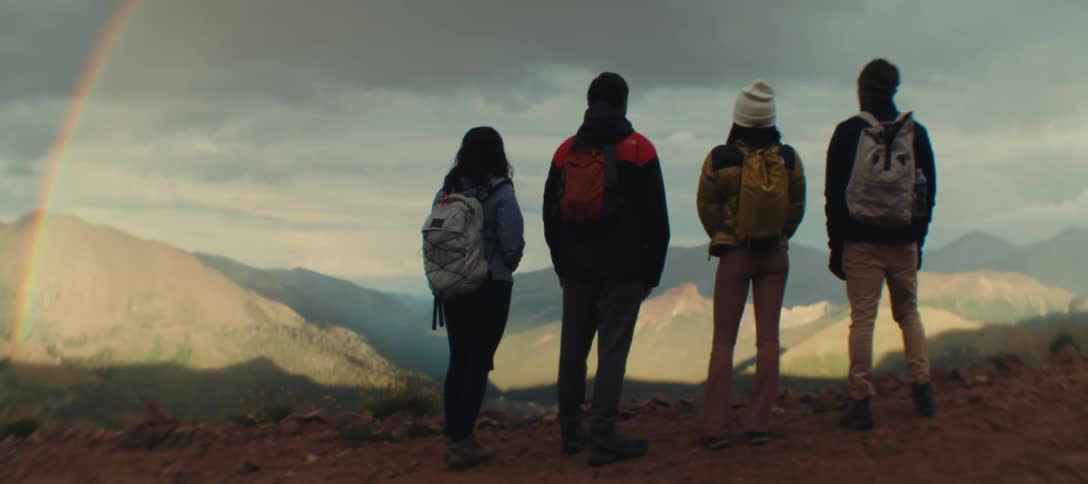 Four hikers with backpacks enjoy a scenic mountain view