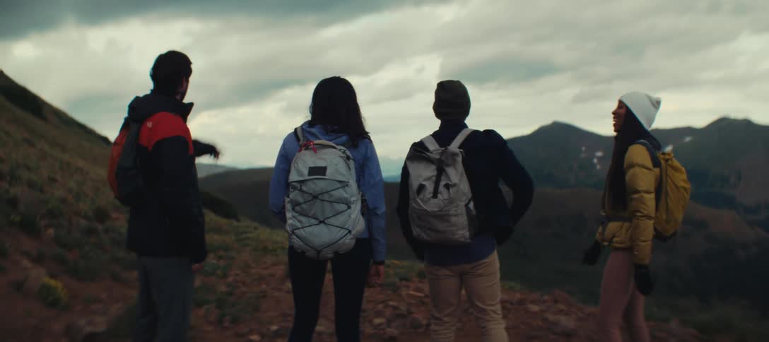 Group of friends with backpacks enjoys the mountain view during the hike