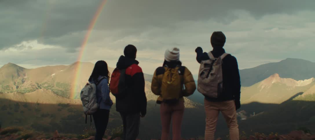 Hikers at the top of a canyon looking out to a double rainbow
