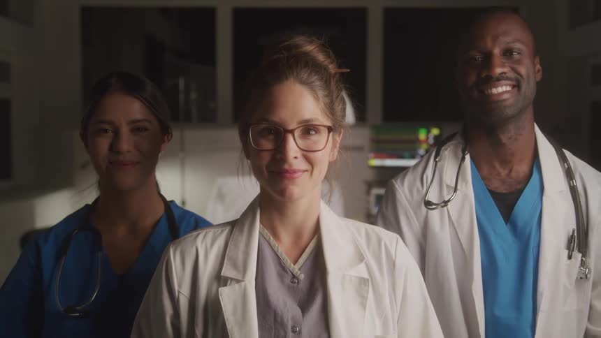 Three doctors a man and two women smiling happily