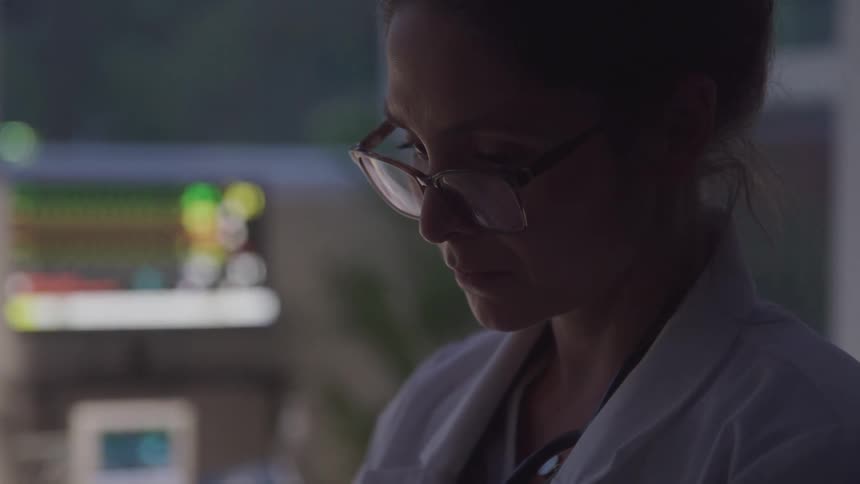 The doctor is reading and writing notes down