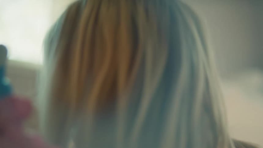 A young child with blonde hair plays with toys indoors
