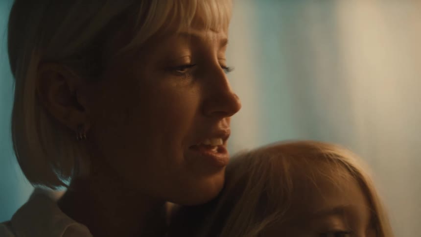 Mother holds her daughter in her lap while reading to the child at home