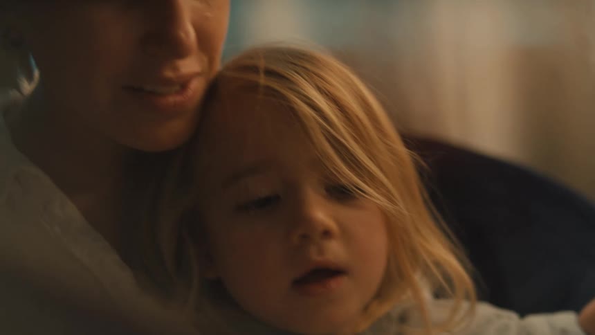 Daughter sits in her mothers lap while being read a story