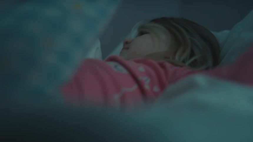 The girl kicks her legs while relaxing in bed