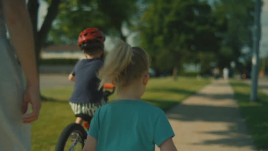 A family walk and ride a bike on the sidewalk