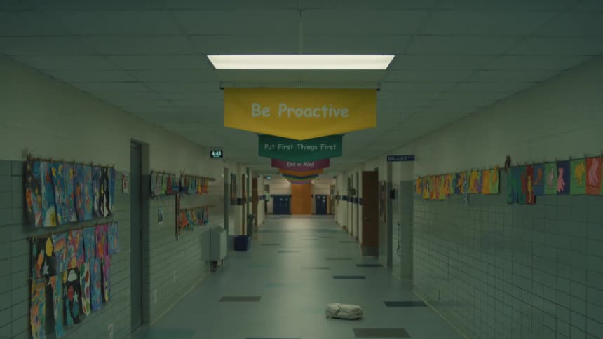 A closeup on a banner that reads the leader in me and then pulls back to reveal a long empty school hallway decorated with more motivational banners and childrens artwork on the walls