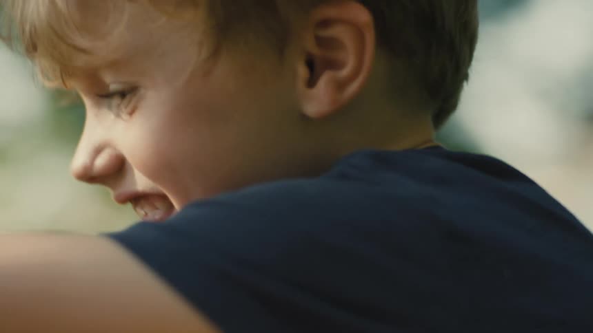 A closeup side profile of a child with blonde hair laughing happily
