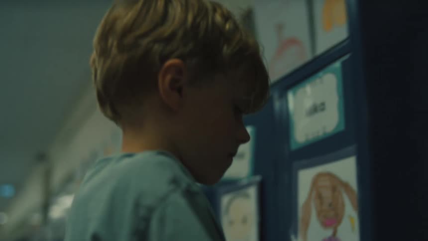 A child with a backpack standing in a school hallway and opening a locker