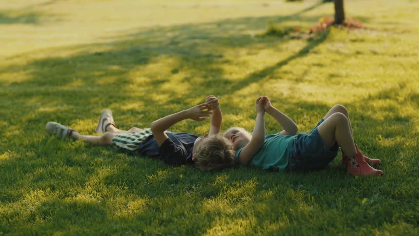 Two children a boy and a girl lying side by side on a patch of green grass relaxing and enjoying a sunny day