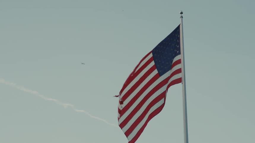 The video shows an american flag hanging on a flagpole against a cloudy sky the flag is rippling gently in a breeze
