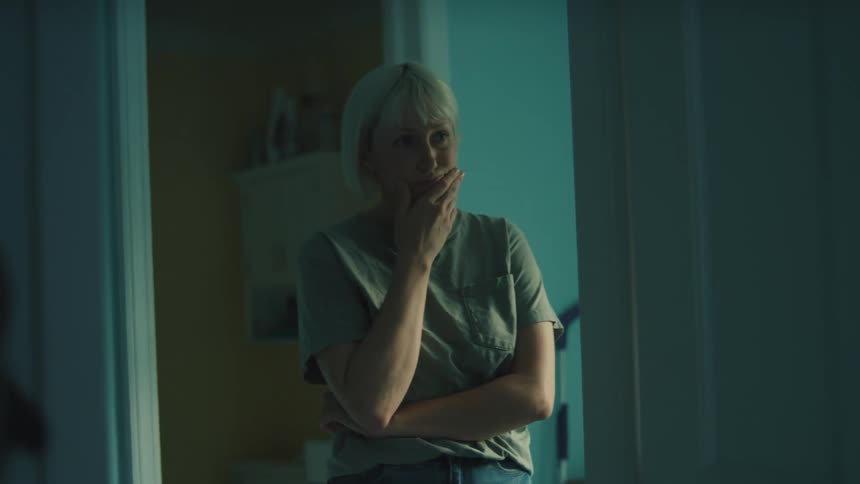 A woman stands in a doorway appearing emotional