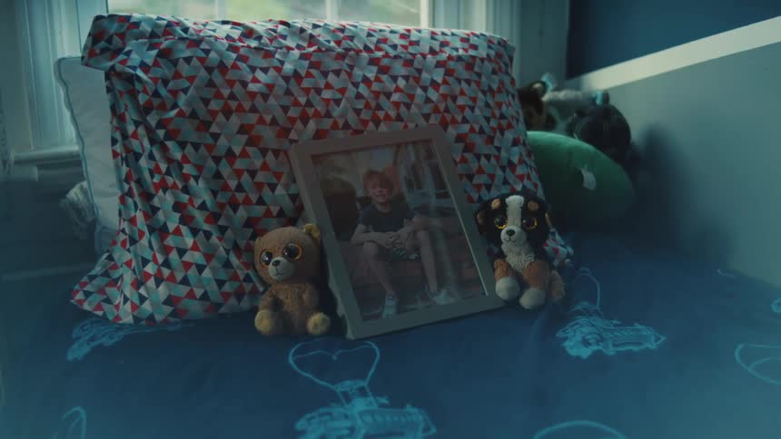 A picture frame rests on a pillow atop a childs bed with stuffed toys on each side of the frame