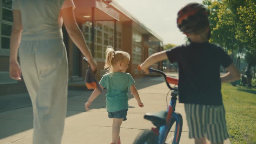 A family are walking towards the park together on a sunny day