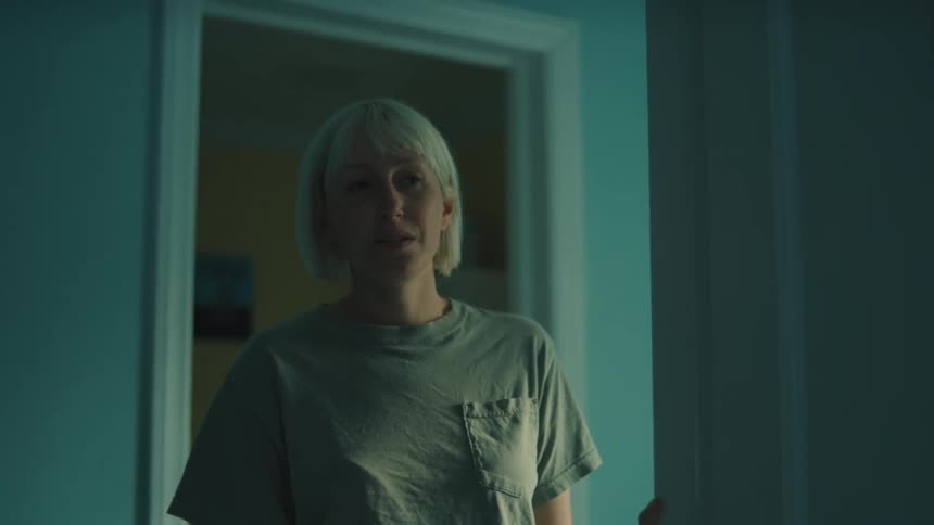 A woman with short blonde hair standing in a doorway