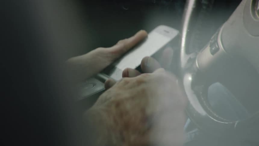 A man smoking in a car while on his phone