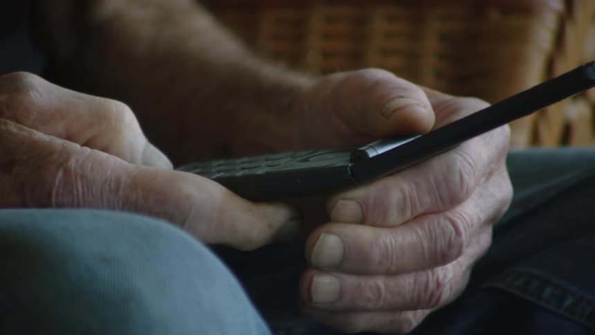 A man is looking at his flip phone