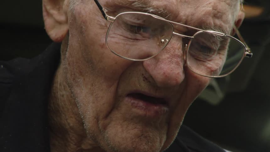 An elderly man looking down trying to read something
