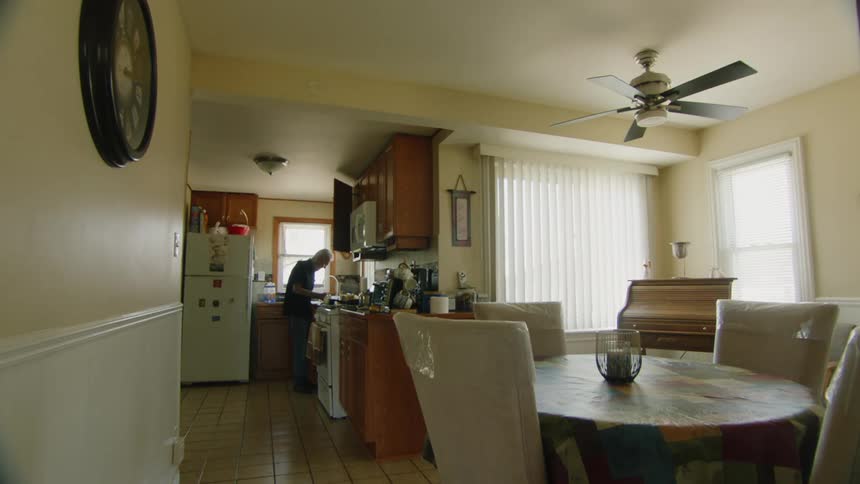 An elderly man is preparing food in the kitchen of a house