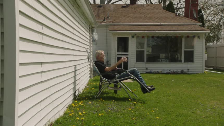 A man is sitting in his yard smoking